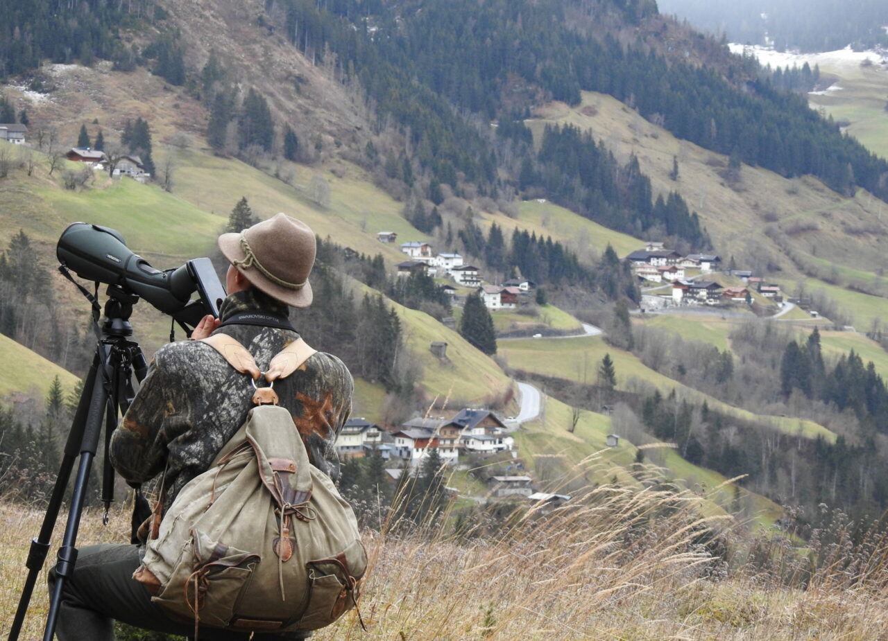 Naturszene mit Mann der mit Handy durchs Spektiv fotografiert